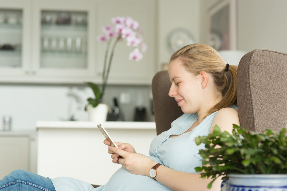 Pregnant woman using phone at home.