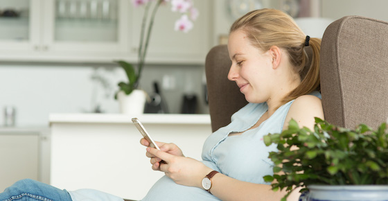 Pregnant woman using phone at home.