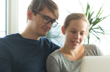 Man and pregnant woman looking at laptop at home.